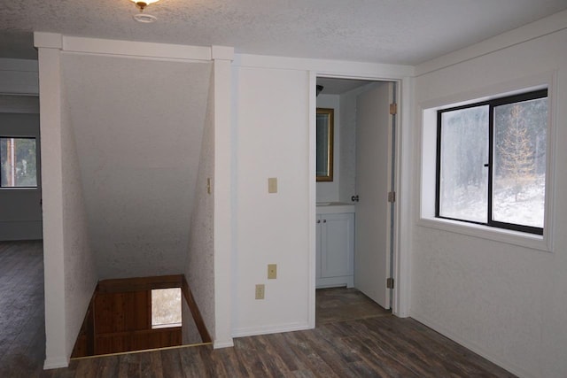 unfurnished bedroom featuring dark hardwood / wood-style floors, a textured ceiling, and multiple windows