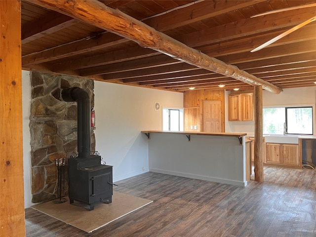 basement featuring wood ceiling, a wood stove, and dark hardwood / wood-style floors