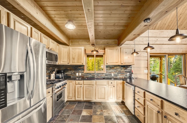 kitchen with beam ceiling, dark tile patterned floors, a healthy amount of sunlight, and appliances with stainless steel finishes