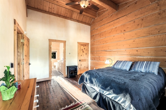 bedroom featuring a wood stove, vaulted ceiling with beams, wooden ceiling, hardwood / wood-style flooring, and ensuite bath