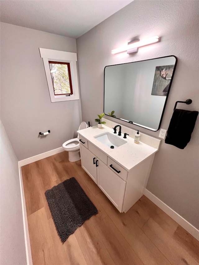 bathroom with toilet, vanity, and hardwood / wood-style flooring