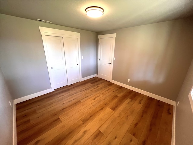 unfurnished bedroom featuring a closet and hardwood / wood-style floors