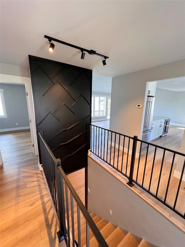 stairs featuring wood-type flooring and rail lighting