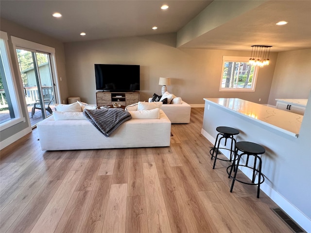 living room featuring a notable chandelier, plenty of natural light, and light hardwood / wood-style floors