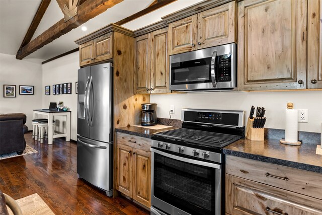 kitchen with appliances with stainless steel finishes, dark stone counters, dark hardwood / wood-style floors, and lofted ceiling with beams