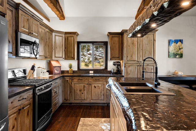 kitchen featuring dark stone counters, gas range oven, dark hardwood / wood-style floors, and beam ceiling