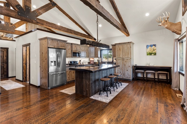 kitchen with stainless steel appliances, a center island, dark stone countertops, and dark wood-type flooring