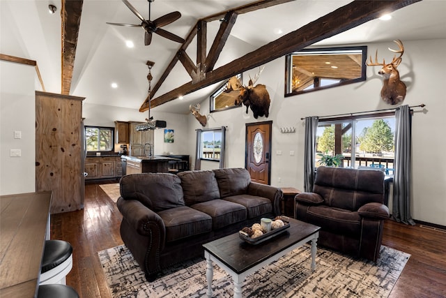 living room featuring a wealth of natural light, ceiling fan, dark wood-type flooring, and beamed ceiling