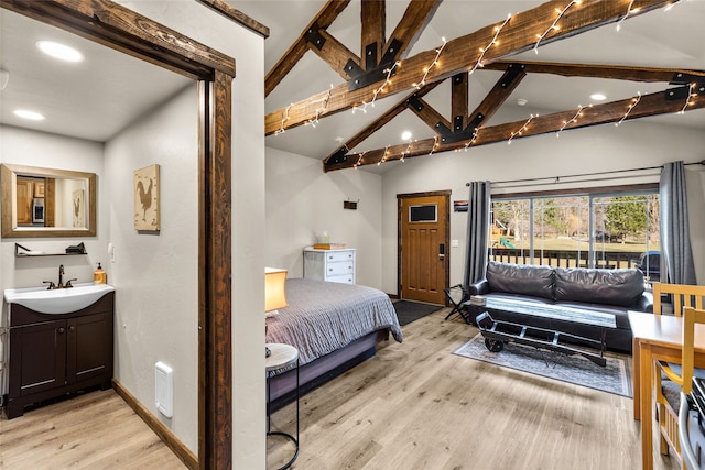 bedroom featuring sink, light wood-type flooring, and lofted ceiling with beams