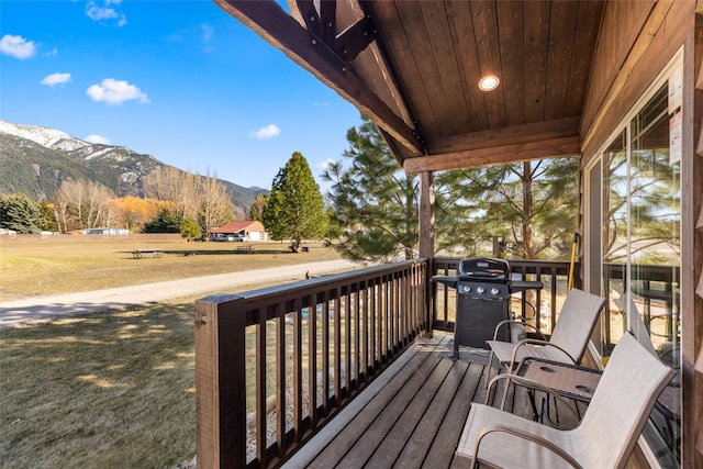 wooden deck with a yard, a mountain view, and grilling area