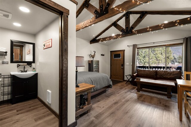 bedroom with lofted ceiling, sink, and light hardwood / wood-style floors