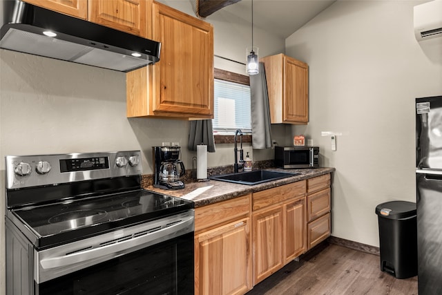 kitchen with appliances with stainless steel finishes, sink, hardwood / wood-style floors, hanging light fixtures, and a wall unit AC