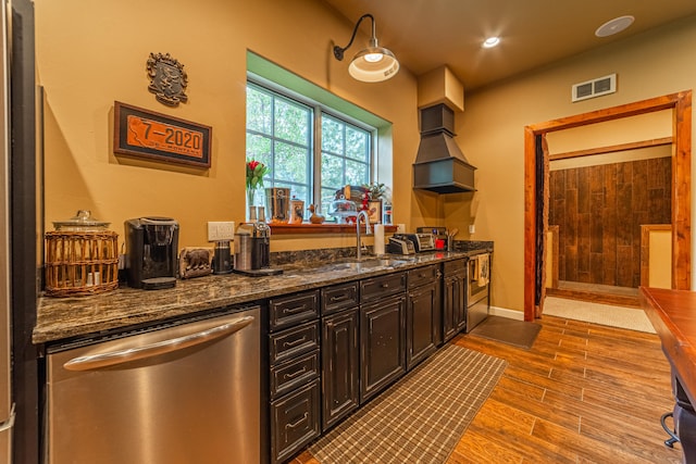 kitchen with appliances with stainless steel finishes, dark stone countertops, light hardwood / wood-style flooring, and custom range hood