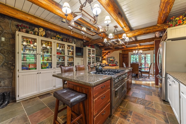 kitchen with appliances with stainless steel finishes, a center island, white cabinets, dark stone counters, and beam ceiling