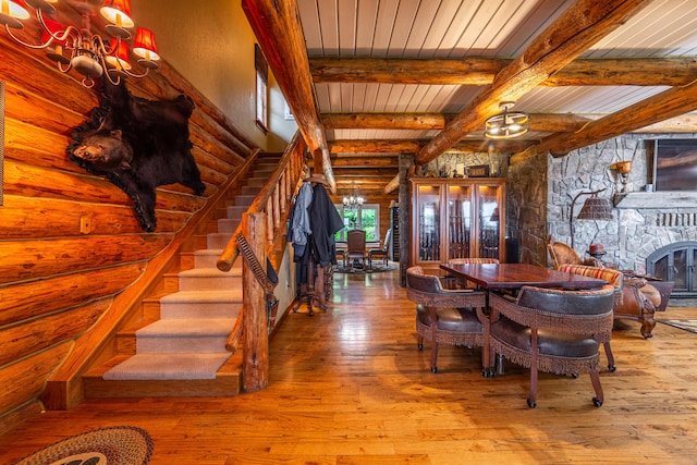 dining space featuring a fireplace, rustic walls, wooden ceiling, hardwood / wood-style floors, and beam ceiling