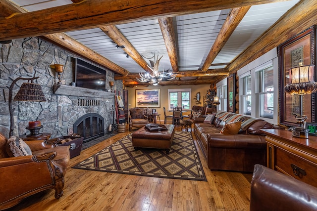 living room with beamed ceiling, light hardwood / wood-style floors, a fireplace, and an inviting chandelier