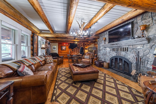 living room featuring beam ceiling, a chandelier, a fireplace, and rustic walls