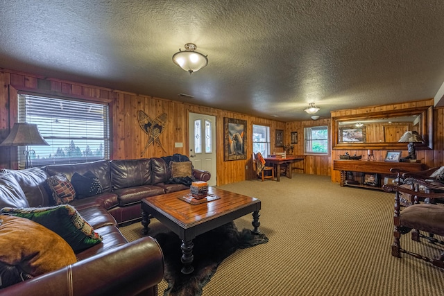 carpeted living room featuring a textured ceiling and wood walls