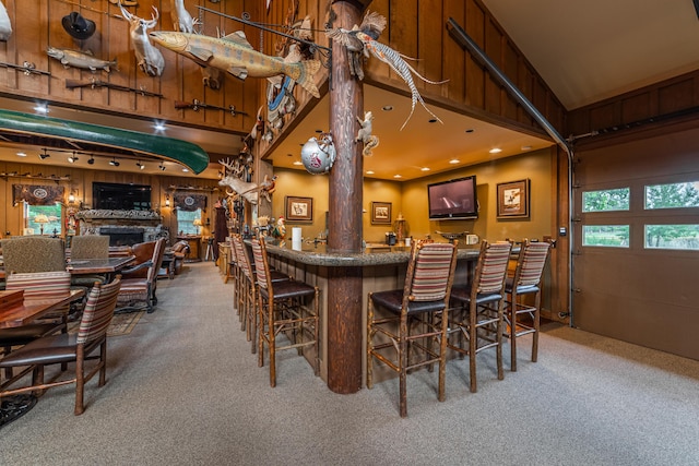 dining area featuring light carpet, bar, and a towering ceiling