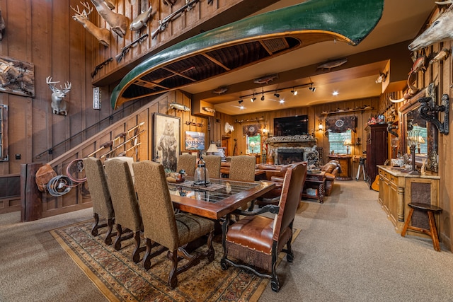 carpeted dining space with wood walls and track lighting