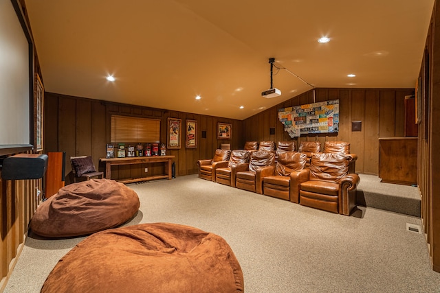 carpeted home theater with wood walls and vaulted ceiling