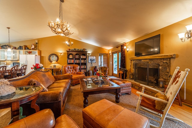 living room with lofted ceiling, light hardwood / wood-style floors, an inviting chandelier, and a stone fireplace