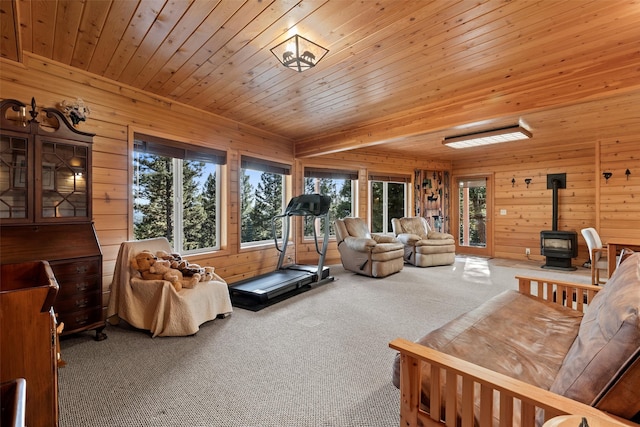 carpeted living room with wood ceiling, a wood stove, and wooden walls