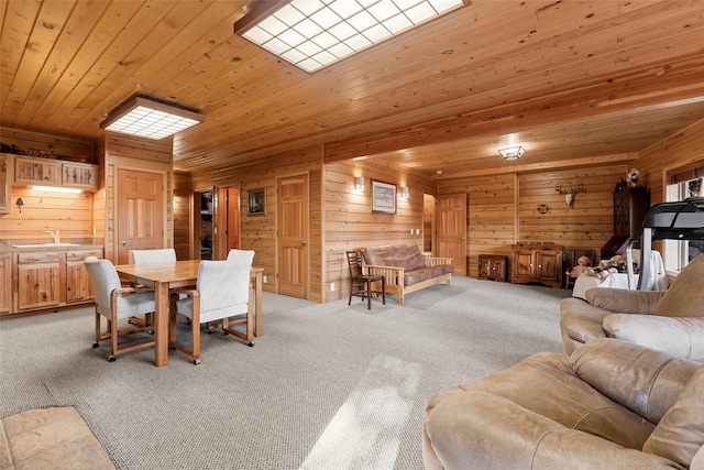 carpeted dining space featuring sink, wood walls, and wood ceiling