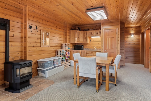 dining room with wooden ceiling, wood walls, sink, and a wood stove