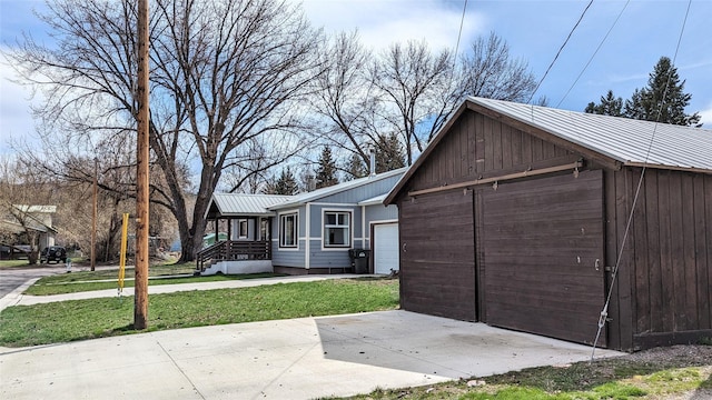 view of front facade featuring a garage, a front yard, metal roof, and an outbuilding