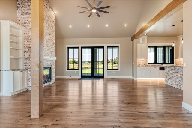 unfurnished living room with light hardwood / wood-style flooring, ceiling fan, high vaulted ceiling, and a fireplace