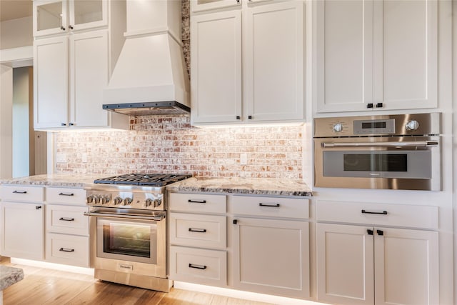 1052 Foxtail Dr, Kalispell, MT 59901 - kitchen featuring white cabinets, appliances with stainless steel finishes, light stone counters, and custom range hood