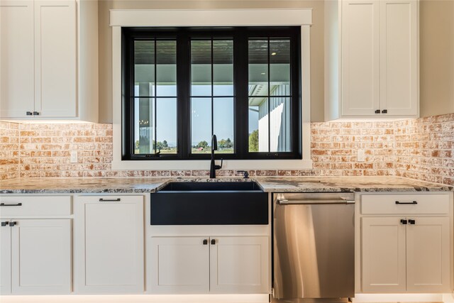 kitchen with light stone countertops, sink, white cabinetry, and stainless steel dishwasher