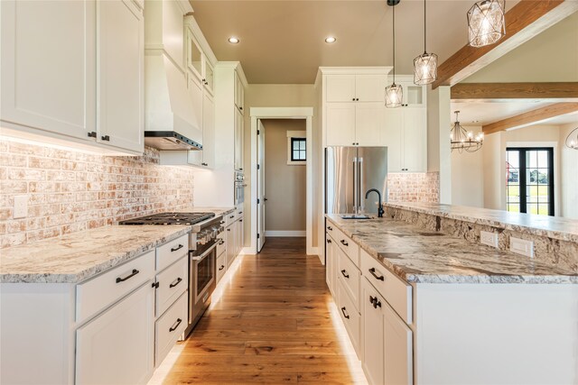 kitchen featuring white cabinets, hanging light fixtures, hardwood / wood-style flooring, custom range hood, and premium appliances