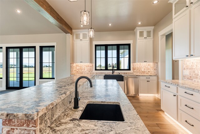 kitchen with light stone counters, dishwasher, plenty of natural light, and beamed ceiling