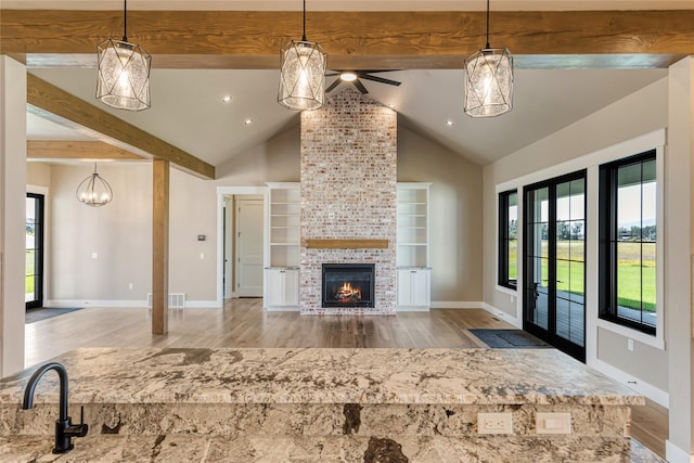 1052 Foxtail Dr, Kalispell, MT 59901 - unfurnished living room featuring baseboards, beamed ceiling, a ceiling fan, wood finished floors, and a large fireplace
