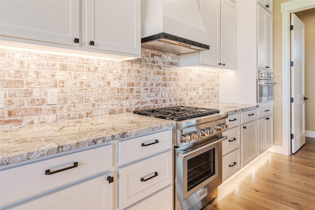 1052 Foxtail Dr, Kalispell, MT 59901 - kitchen featuring white cabinets, light stone countertops, wall chimney exhaust hood, and appliances with stainless steel finishes