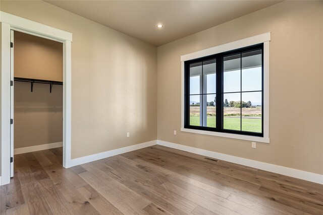 unfurnished bedroom with hardwood / wood-style flooring, a walk in closet, and a closet