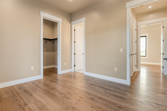 unfurnished bedroom featuring a walk in closet, a closet, and light hardwood / wood-style flooring