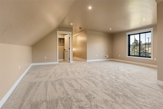 bonus room with vaulted ceiling and light colored carpet