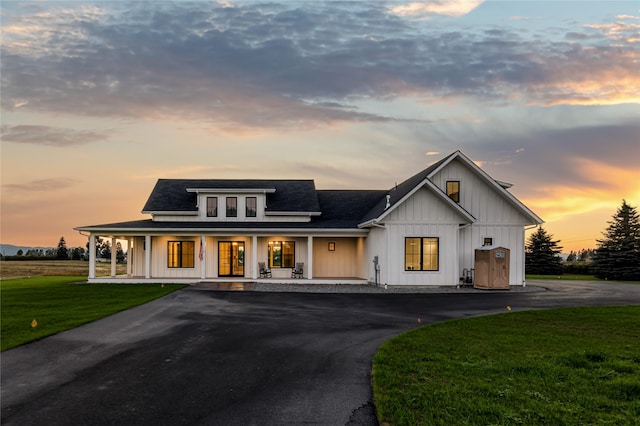 1052 Foxtail Dr, Kalispell, MT 59901 - modern inspired farmhouse featuring aphalt driveway, a shingled roof, a yard, board and batten siding, and a porch