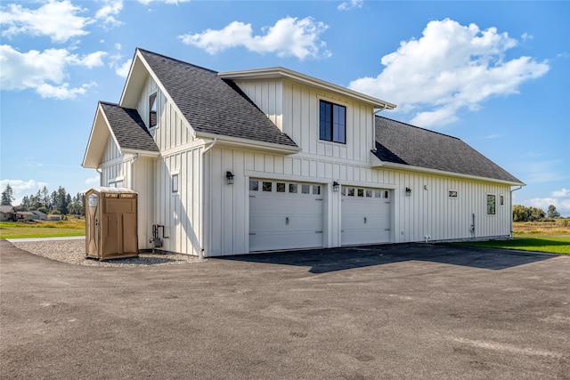 1052 Foxtail Dr, Kalispell, MT 59901 - view of property exterior featuring board and batten siding, driveway, roof with shingles, and a garage