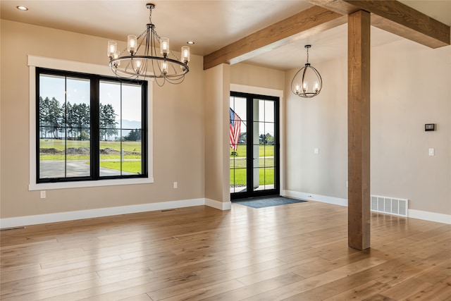 empty room featuring french doors, light hardwood / wood-style floors, an inviting chandelier, and beam ceiling