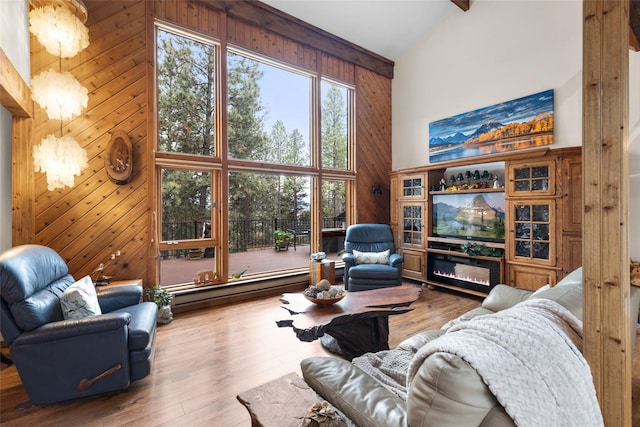 living room with a baseboard heating unit, hardwood / wood-style floors, wood walls, and a high ceiling