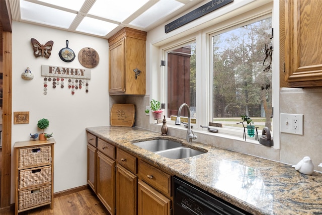 kitchen with dishwasher, light stone countertops, sink, and light hardwood / wood-style flooring