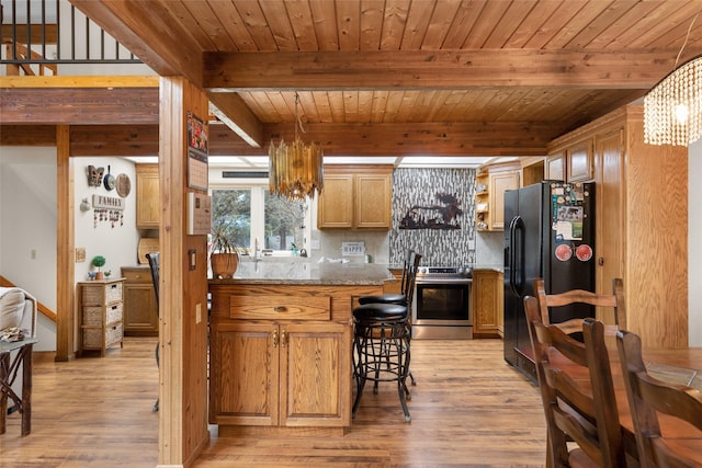 kitchen with black fridge, stainless steel range oven, light hardwood / wood-style floors, and decorative backsplash