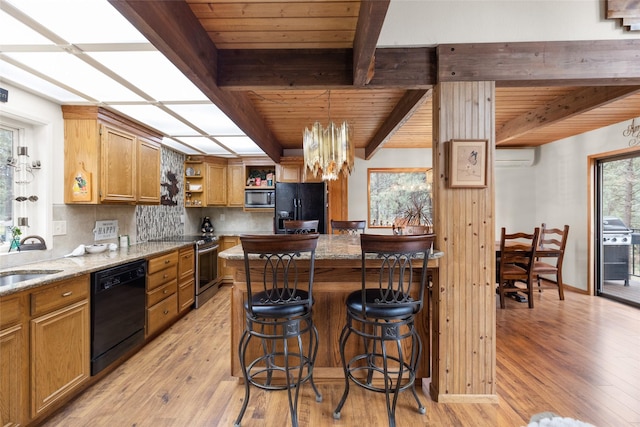 kitchen featuring light stone counters, backsplash, a wall mounted AC, and black appliances