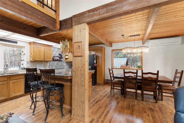 kitchen featuring pendant lighting, sink, hardwood / wood-style floors, a wall mounted AC, and black fridge