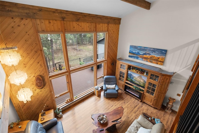 living room featuring an inviting chandelier, hardwood / wood-style floors, wooden walls, and beamed ceiling