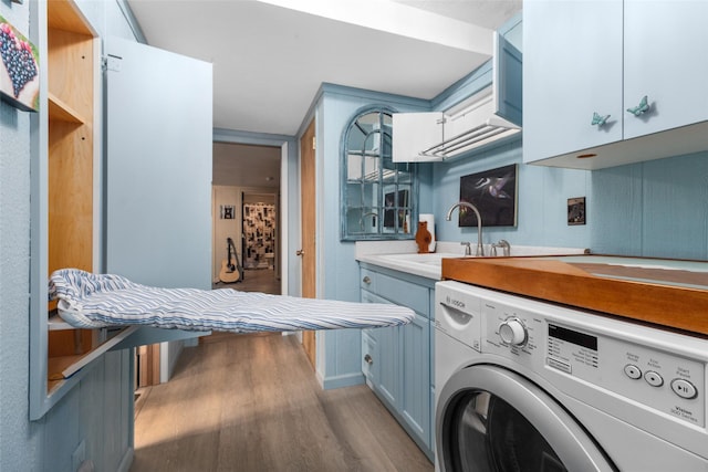 clothes washing area with light hardwood / wood-style floors, cabinets, washer / dryer, and sink